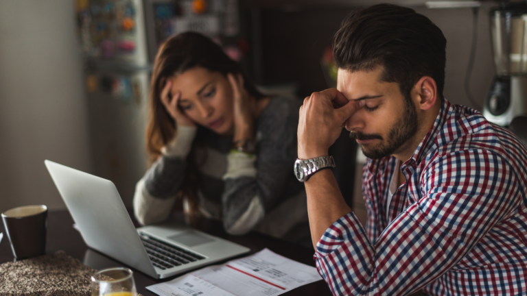 Image of a woman in front of a notebook next to a man whose appearance shows concern.