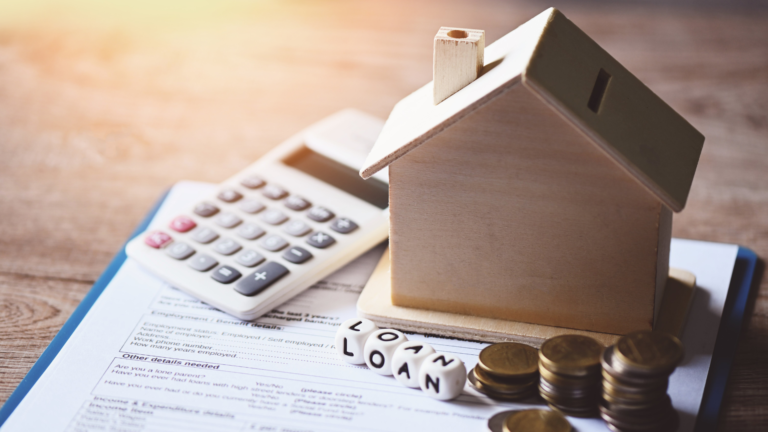 Illustrative image with calculator, wooden house and piles of coins.