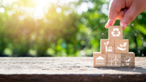 A hand fitting together wooden blocks containing symbols reminiscent of sustainable companies.